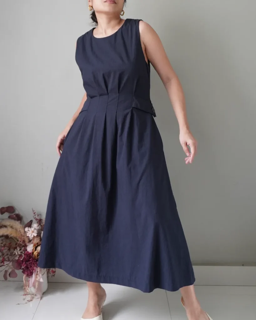 It’s deep blue sleeveless dress with functional pockets, pleat details, easy back zipper